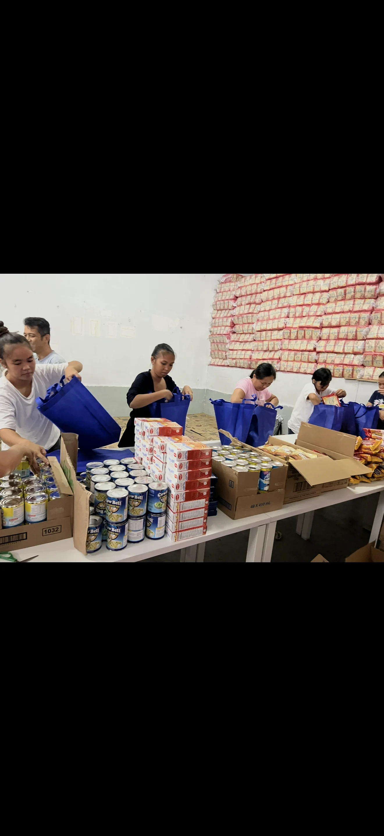 Team packing canned goods and grocery items into blue bags